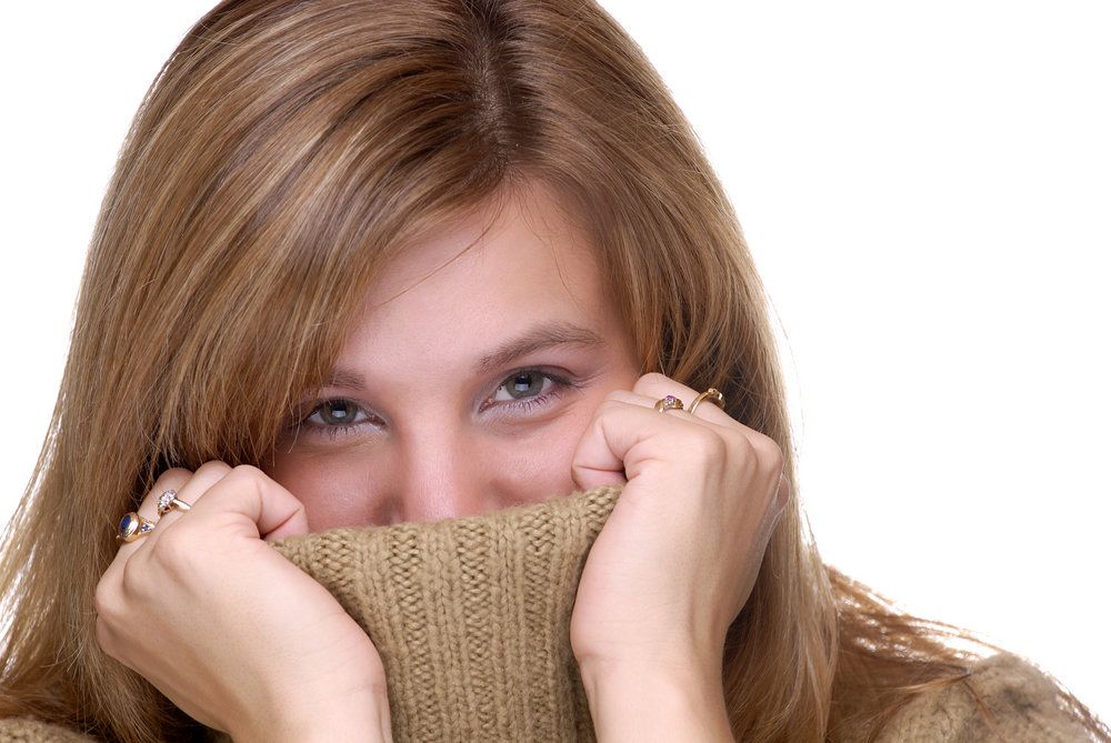 Young woman hiding mouth under turtleneck sweater